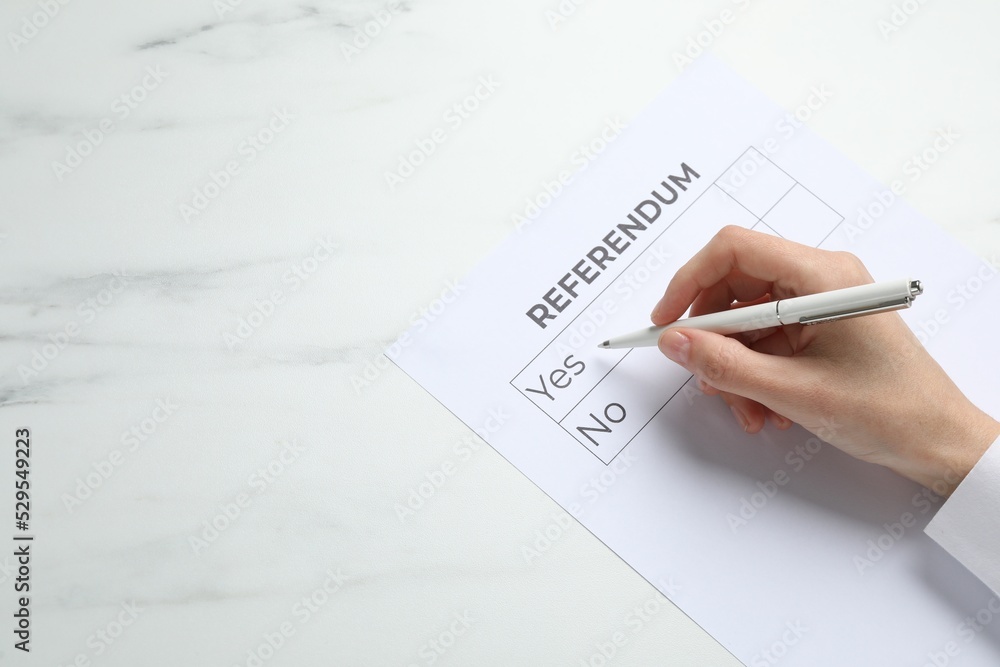 Woman with referendum ballot making decision at white marble table, closeup. Space for text Woman with referendum ballot making decision at white marble table, closeup. Space for text