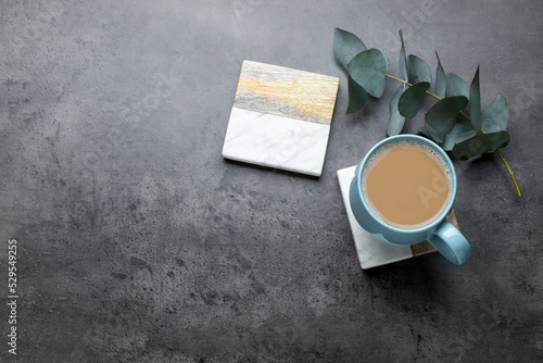 Mug of coffee, stylish cup coasters and eucalyptus branch on grey table, flat lay. Space for text