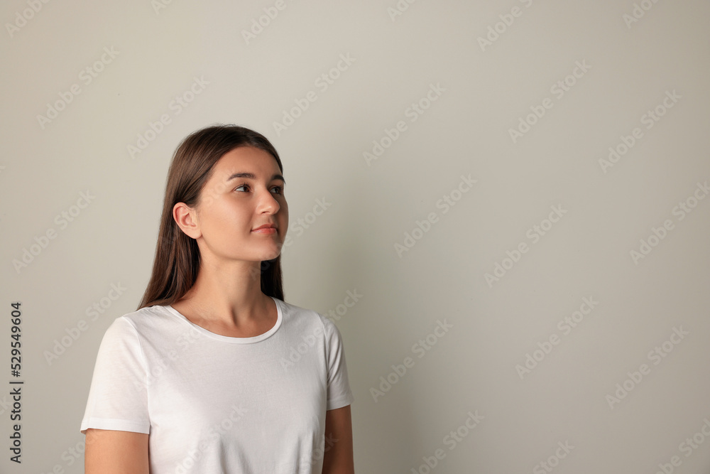 Fototapeta premium Beautiful young woman in white t-shirt on light background. Space for text