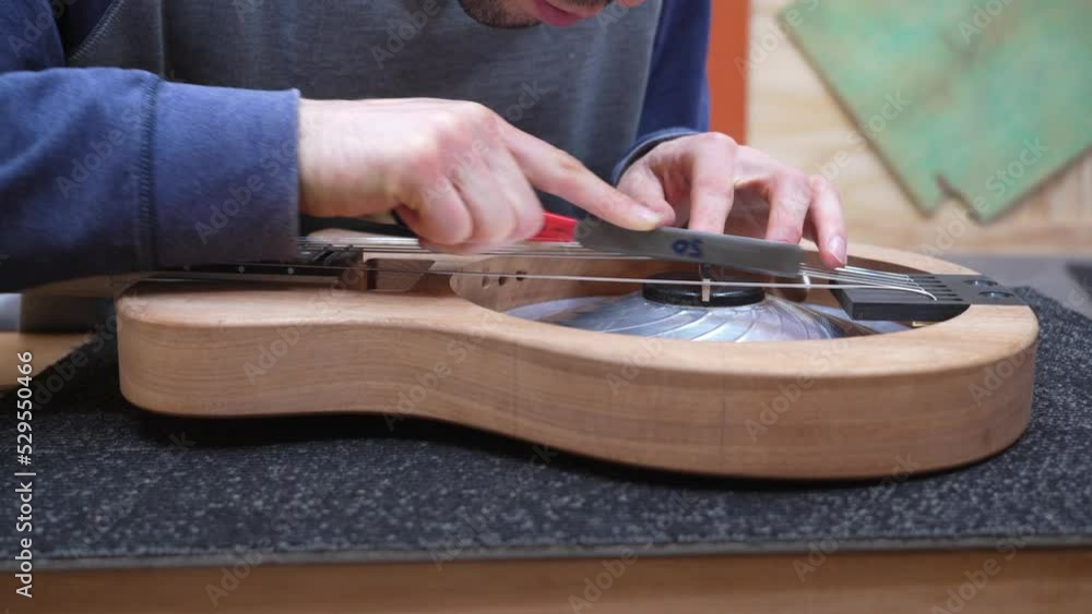 Luthier setting saddle height after attaching strings on newly built electric resonator. Close up. Luthier setting saddle height after attaching strings on newly built electric resonator. Close up.
