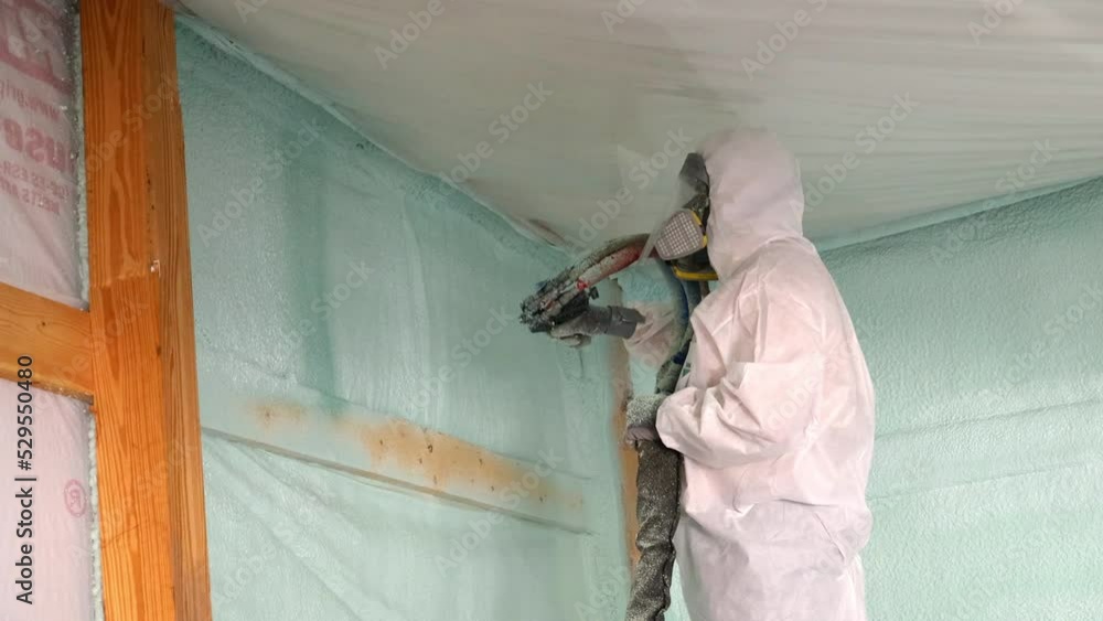 Stockvideon Worker in respirator and Tyvek suit sprays closed cell foam