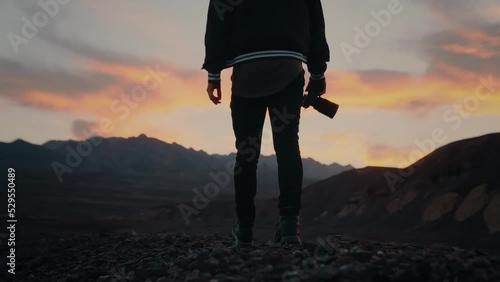 Photographer at sunset with camera in hand on badlands ridge, Death Valley