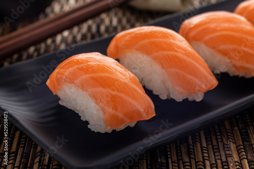 Salmon or sake nigiri sushi, a mold of rice with toppings of raw salmon slices, served on a rectangular serving plate, close-up. Saki nigiri sushi is one of popular Japanese food dishes. photo