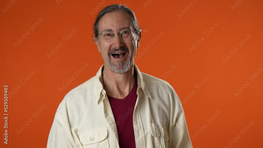 Portrait of smiling happy mature man on on laptop saying wow and giving thumbs up using computer on solid orange background. Portrait of smiling happy mature man on on laptop saying wow and giving thumbs up using computer on solid orange background.