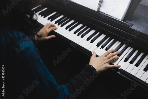 Close up of woman's hands playing piano by reading sheet music. Selective focus