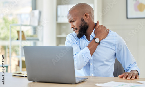Black man, shoulder pain on laptop in stress and injury suffering from overworking at home. Stressed African male holding sore muscle, tension or joint inflammation sitting with computer and work