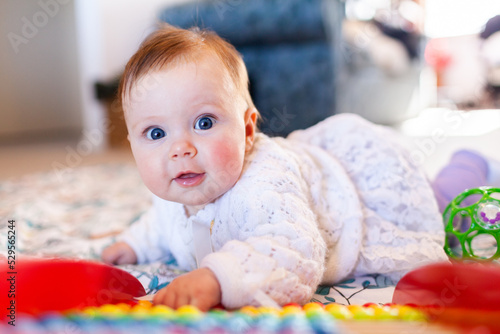 Happy baby girl with bright blue eyes playing with colourful abacus beads photo