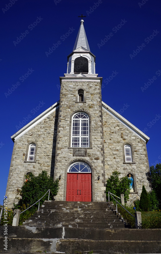 Fototapeta premium Facade and steeple of an old stone Roman Catholic church in a village in western Quebec