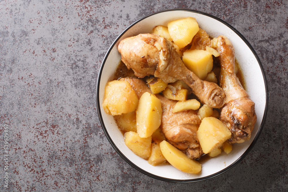 Indonesian cuisine chicken drumsticks stewed with potatoes in spicy sweet soy sauce close-up on the table. horizontal top view from above Indonesian cuisine chicken drumsticks stewed with potatoes in spicy sweet soy sauce close-up on the table. horizontal top view from above