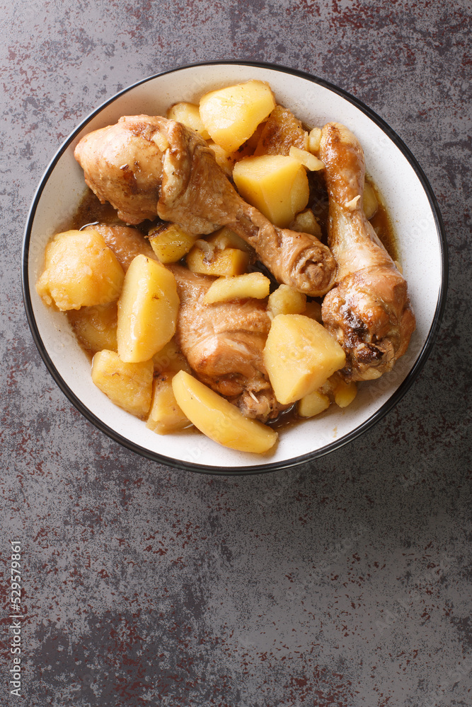 Chicken drumsticks stewed with potatoes in a spicy sweet sauce Indonesian food close-up on the table. Vertical top view from above Chicken drumsticks stewed with potatoes in a spicy sweet sauce Indonesian food close-up on the table. Vertical top view from above