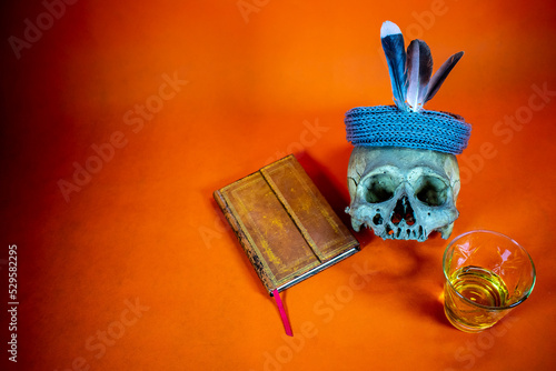 Orange background with old books, a skull and a glass of liquor. space to insert text photo