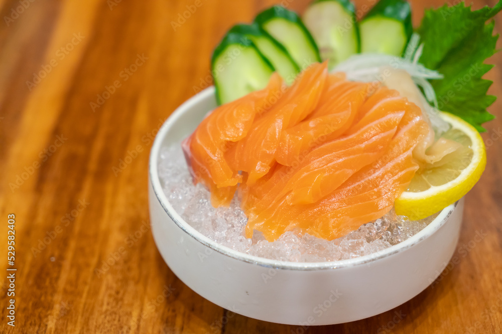 Salmon Sashimi, Japanese food, served with sliced cucumber and lemon over ice. Salmon Sashimi, Japanese food, served with sliced cucumber and lemon over ice.