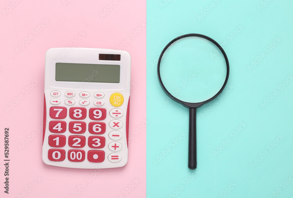 Calculator with a magnifying glass on a blue-pink pastel background. Business concept. Top view Calculator with a magnifying glass on a blue-pink pastel background. Business concept. Top view