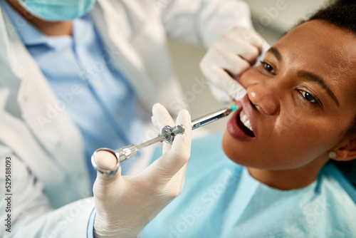 Black woman receives anesthetic at dentist's office.
