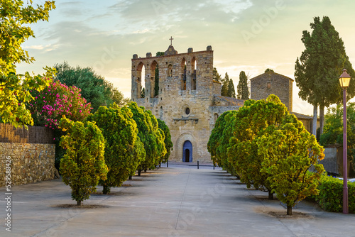 Fotobehang Old stone church with walk with trees at sunset in the town of Peratallada, Girona, Spain