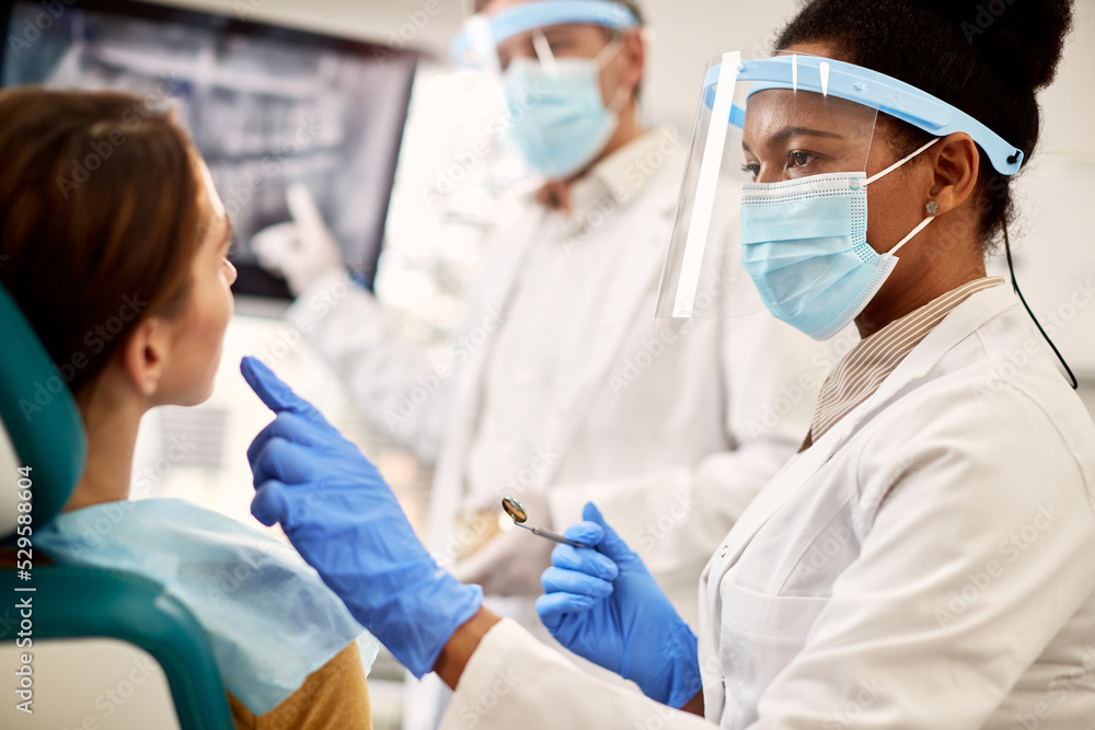 African American female dentist examining woman's teeth during appointment at dental clinic. African American female dentist examining woman's teeth during appointment at dental clinic.