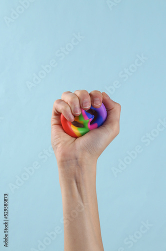 Woman's hand squeezing antistretch sensory Snappers toy on a blue background