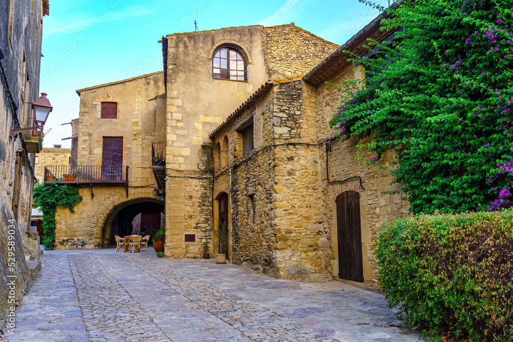 Medieval stone houses with green vines at sunset on a summer day, Peratallada, Girona, Catalonia.