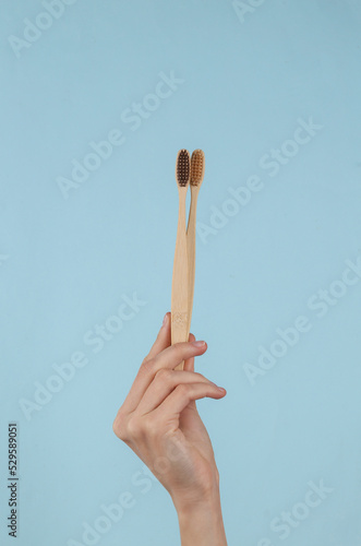 Eco Bamboo Toothbrushes in female hand on a blue background. Dental care