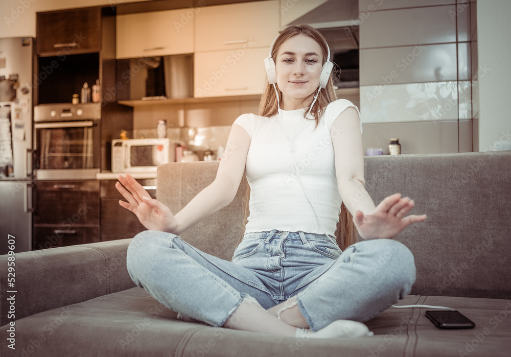 Young attractive woman listening to music while sitting on the sofa in the living room. Relax