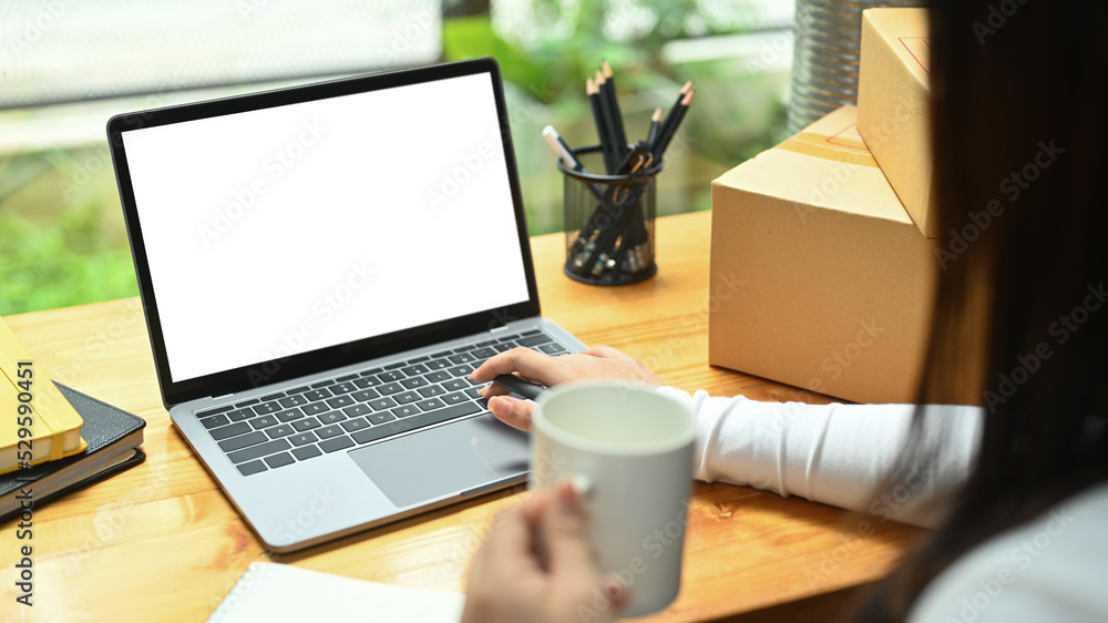 Fototapeta premium Young woman checking product purchase order on laptop computer. E-Commerce, online business, online sales concept