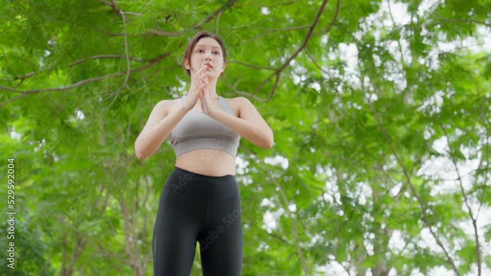 Asian woman is engaged in fitness and stretching in public park. Sporty woman does exercises in the open air. Healthy lifestyle, sports outdoor activities in park Asian woman is engaged in fitness and stretching in public park. Sporty woman does exercises in the open air. Healthy lifestyle, sports outdoor activities in park