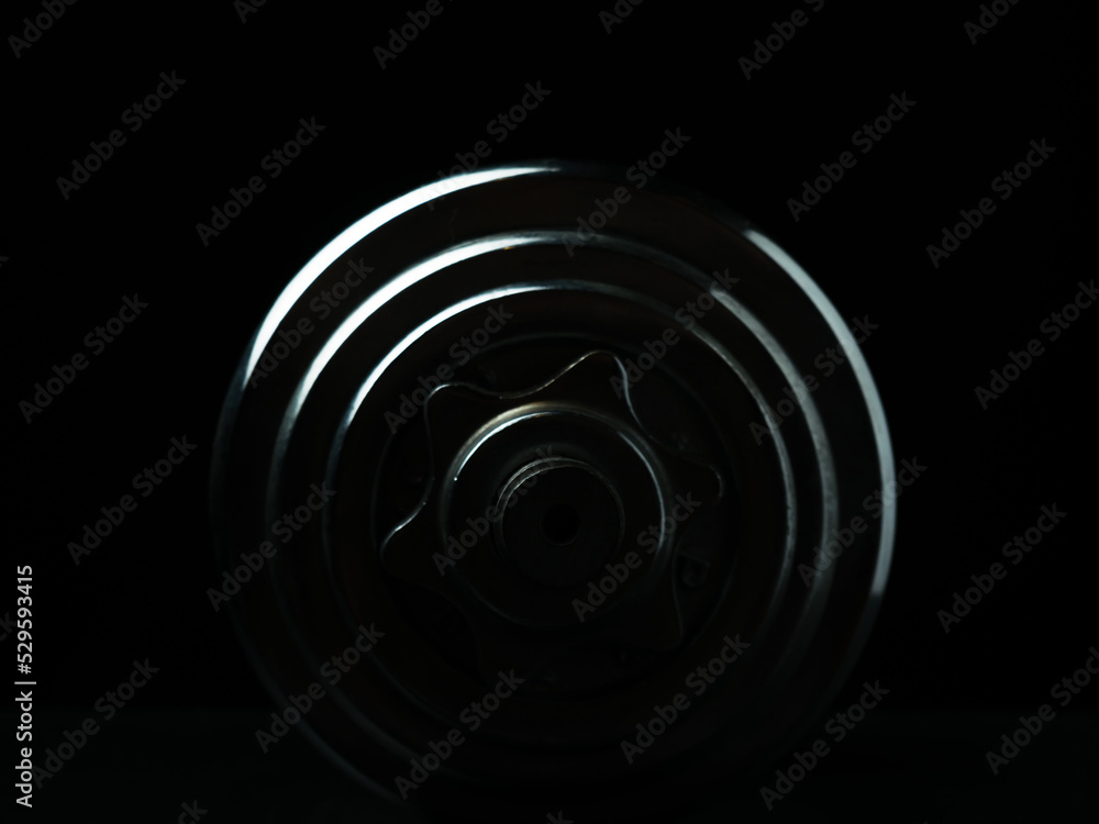 Stainless steel dumbbell on dark background. Stainless steel dumbbell on dark background.