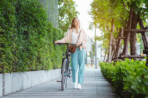 Happy Asian young woman walk and ride bicycle in park, street city her smiling using bike of transportation, ECO friendly, People lifestyle concept.. photo