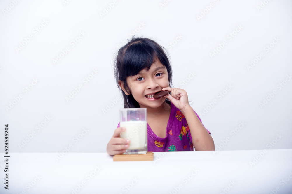 Happy little girl eating biscuits with milk fresh milk for breakfast Happy little girl eating biscuits with milk fresh milk for breakfast