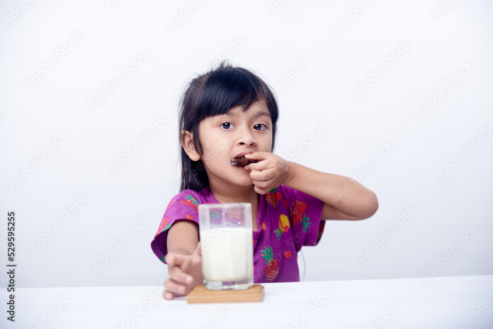 Happy little girl eating biscuits with milk fresh milk for breakfast Happy little girl eating biscuits with milk fresh milk for breakfast