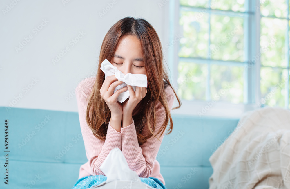 Asian young woman patient cold sick she sneeze with tissue paper on sofa, Female health problem blowing nose use pharmacy first aid box delivery service hospital, self recover health care concept. Asian young woman patient cold sick she sneeze with tissue paper on sofa, Female health problem blowing nose use pharmacy first aid box delivery service hospital, self recover health care concept.