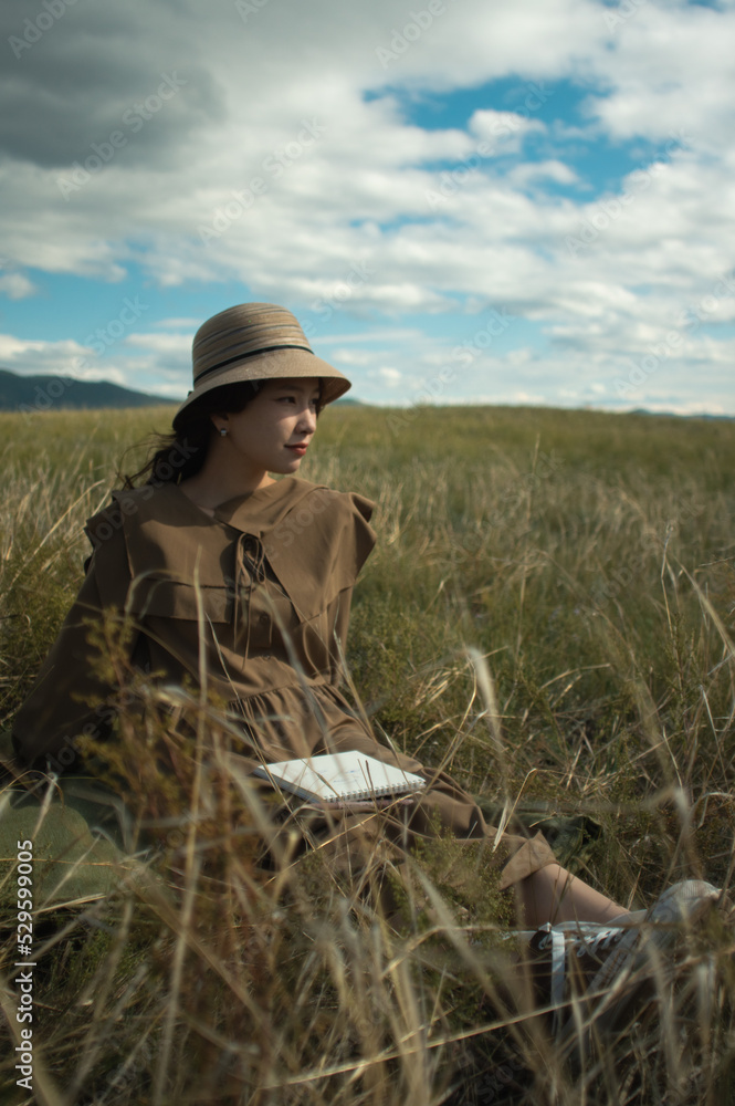 young lady with sketch book on the meadow looking side young lady with sketch book on the meadow looking side