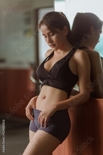 asian slim fitness woman working out in gym with portrait of fitness woman in gym posing for lean body and healthy lifestyle concept