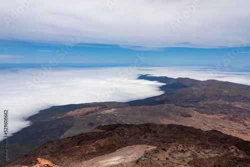 Scenic view from summit of volcano Pico del Teide over the island of Tenerife, Canary Islands, Spain, Europe. Vista on barren landscape, solidified lava, ash, pumice. Valley and sea covered in clouds