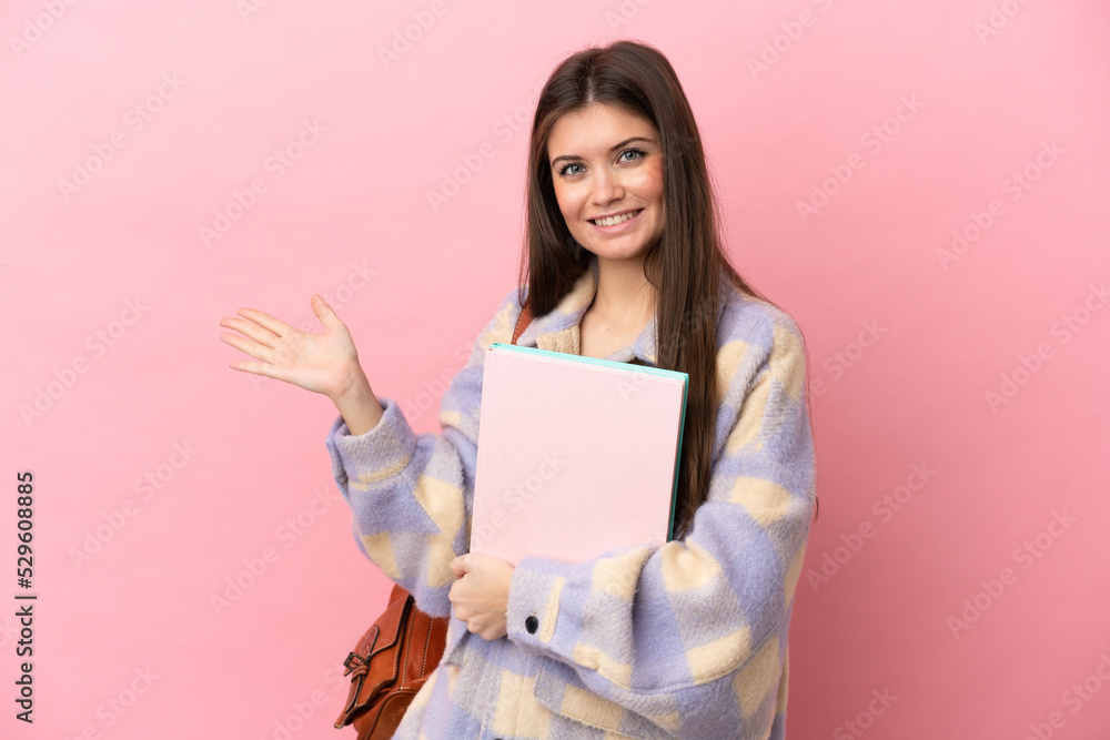 Young student woman isolated on pink background extending hands to the side for inviting to come Young student woman isolated on pink background extending hands to the side for inviting to come
