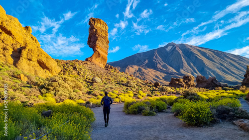 Man with backpack hiking with scenic golden hour sunrise morning view on unique rock formation Roque Cinchado, Roques de Garcia, Tenerife, Canary Island, Spain, Europe. Pico del Teide volcano summit photo