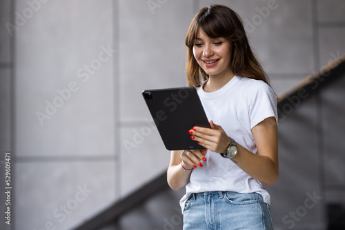 Beautiful caucasian woman sitting on sofa in living room and using tablet. Apartment interior. © F8  \ Suport Ukraine