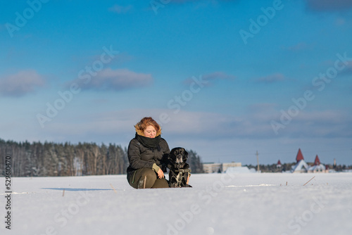 A young beautiful girl walks a purebred Labrador on a snowy field. There is artistic noise.