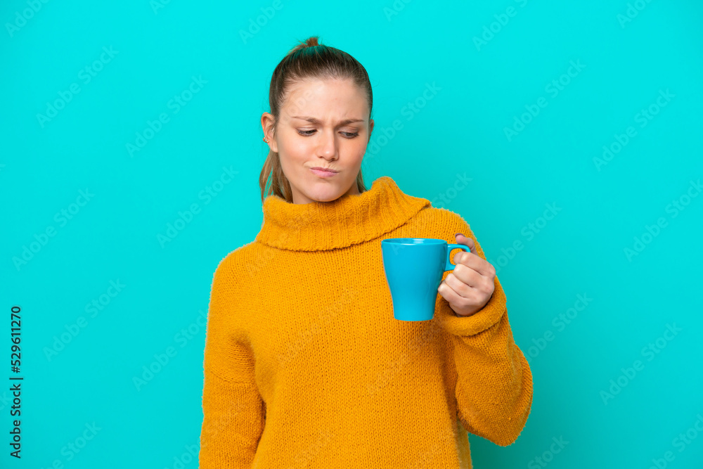 Young caucasian woman holding cup isolated on blue background with sad expression Young caucasian woman holding cup isolated on blue background with sad expression