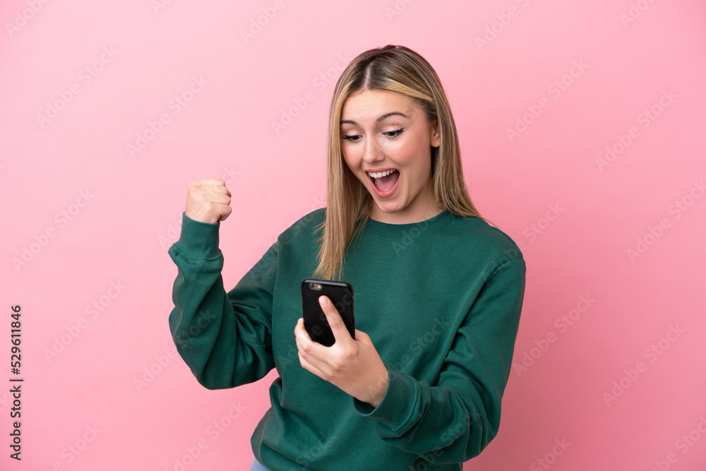 Young caucasian woman isolated on pink background with phone in victory position Young caucasian woman isolated on pink background with phone in victory position