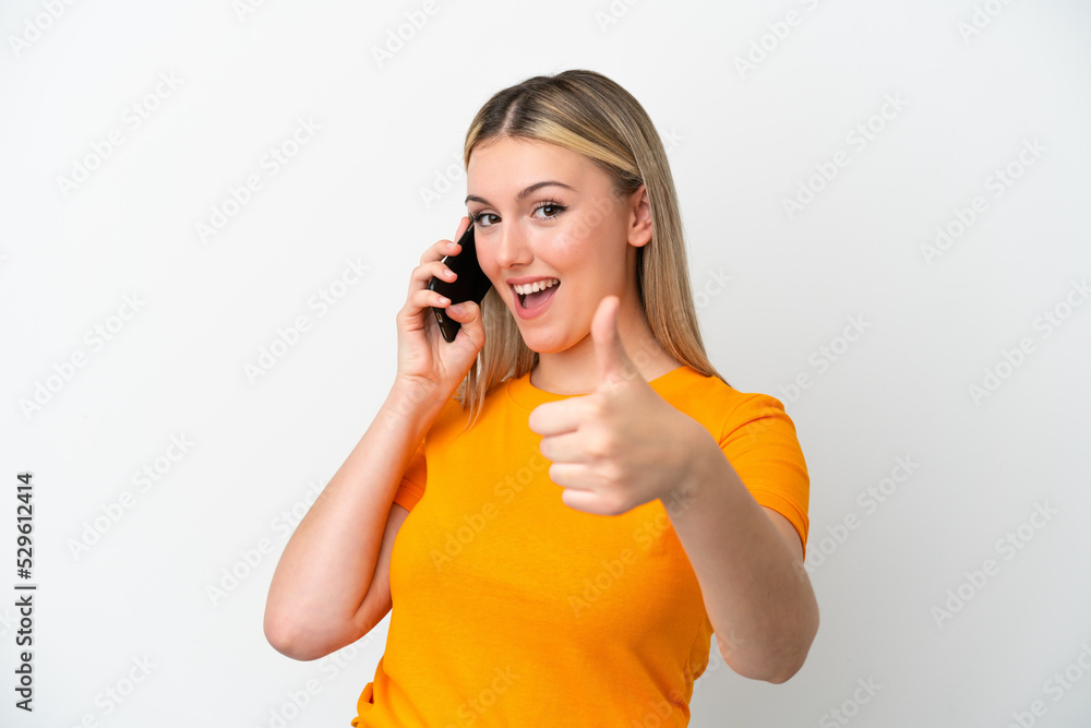 Young caucasian woman isolated on white background keeping a conversation with the mobile while doing thumbs up Young caucasian woman isolated on white background keeping a conversation with the mobile while doing thumbs up
