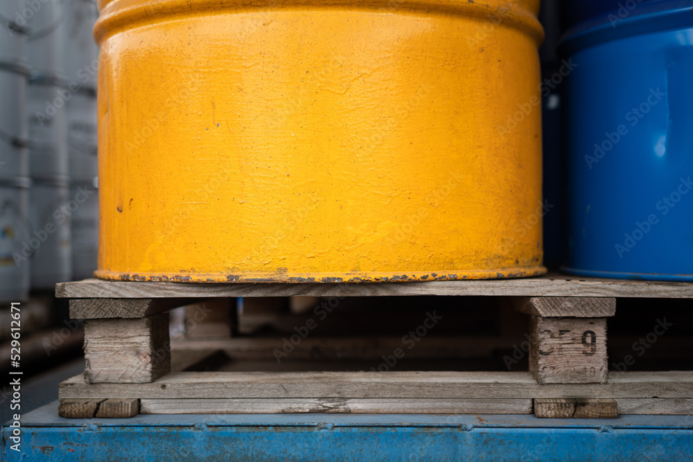 Close-up at wood pallet with metal chemical barrels at the factory storage. Industrial equipment object photo, selective focus. Close-up at wood pallet with metal chemical barrels at the factory storage. Industrial equipment object photo, selective focus.