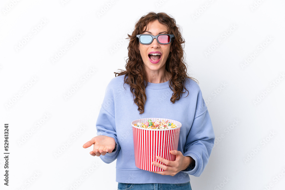 Young woman with curly hair isolated on white background with 3d glasses and holding a big bucket of popcorns