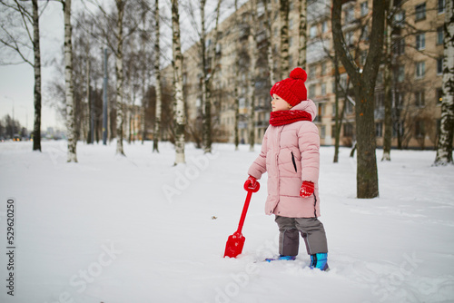 Adorable preschooler girl having fun in beautiful winter park on a snowy cold winter day