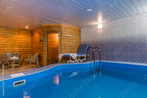 The modern interior of the SPA center with a blue pool and a wooden bath. © alhim