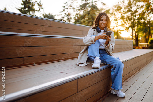 Young woman listening to music with headphones outdoors. The concept of people, music, emotions.