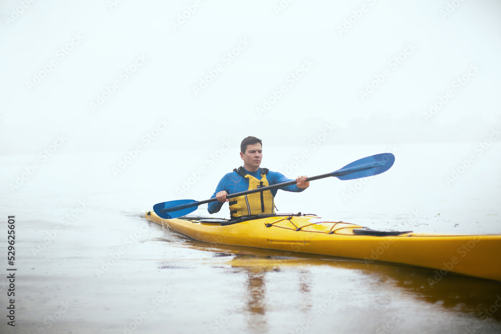 One man paddling kayak at autumn misty river at foggy autumn morning. One man paddling kayak at autumn misty river at foggy autumn morning.