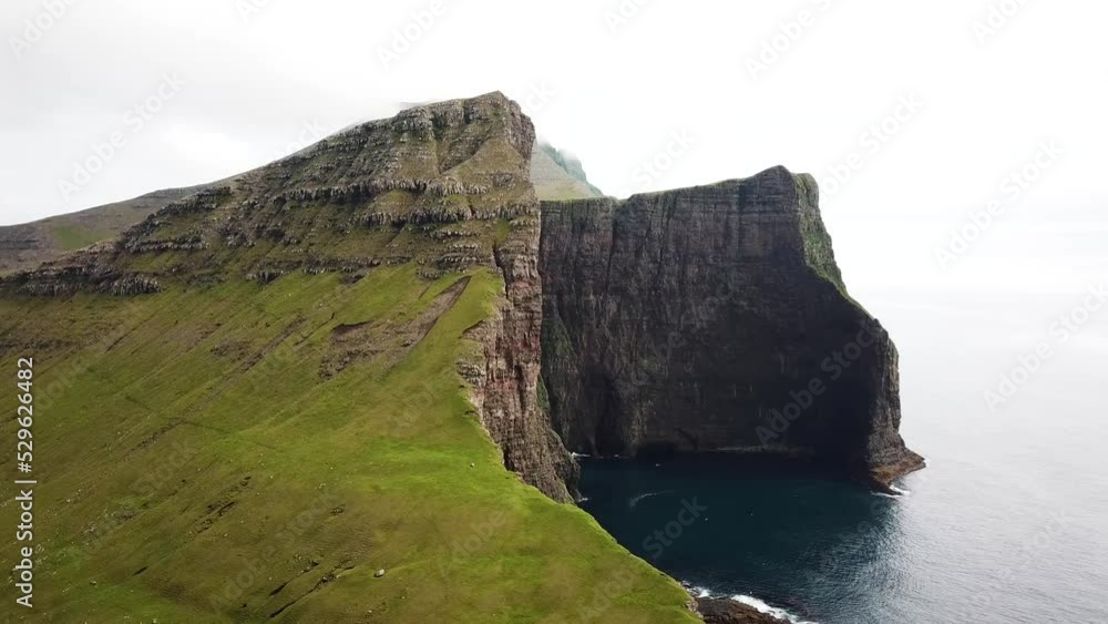 Aerial drone view of huge cliffs near Drangarnir and Tindholmur, Faroe Islands. Amazing Faroese nature, green hills and beautiful rocky cliffs and mountains. Sunny day in summer. Quality 4k footage. Aerial drone view of huge cliffs near Drangarnir and Tindholmur, Faroe Islands. Amazing Faroese nature, green hills and beautiful rocky cliffs and mountains. Sunny day in summer. Quality 4k footage.
