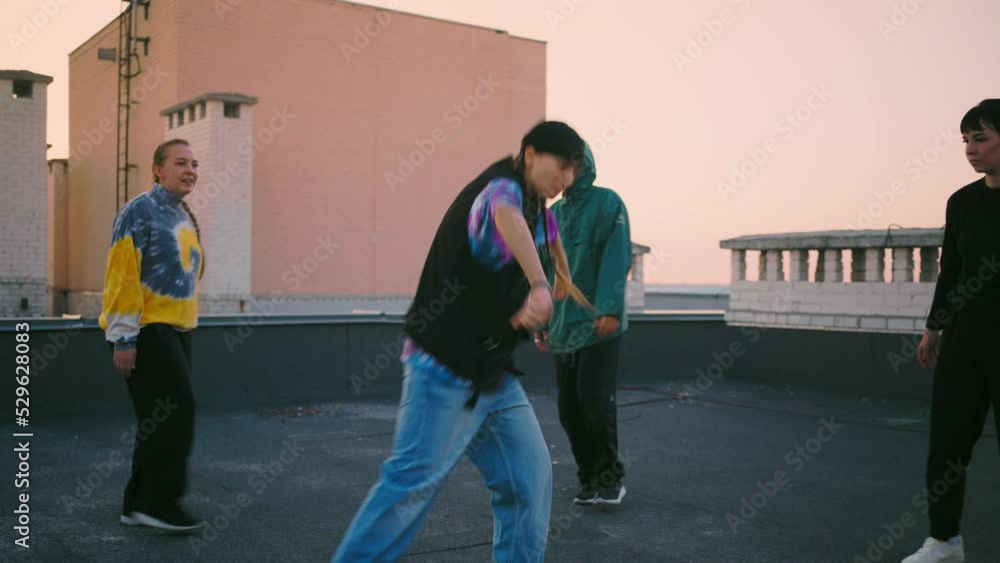 stylish teen b-girl is dancing in round of friends on roof in sunset, teens party and street dance battle