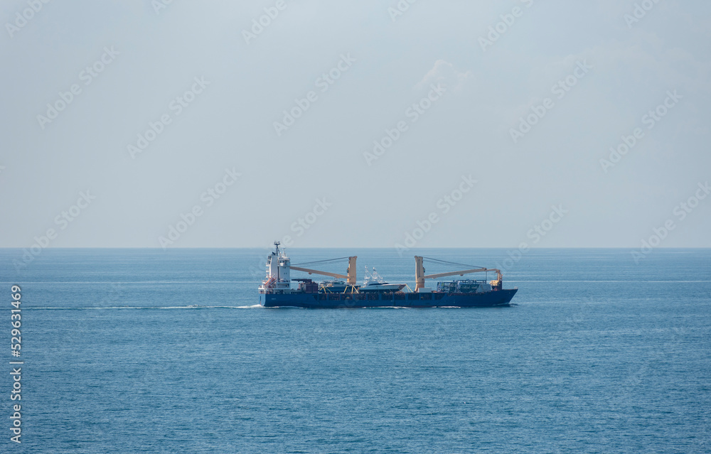 Small cargo ship sailing through the calm sea. 